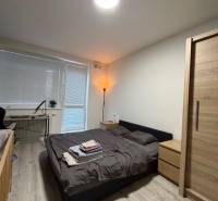 Hálószoba egy kétszobás lakásban fa dekorációjú padlóval és az ablak melletti ággyal.