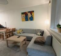 Világos nappali sarokkanapéval és művészettel egy kétszobás lakásban.