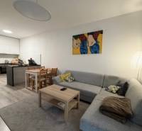 Nappali rész egy kétszobás lakásban kanapéval, asztallal és étkező sarokkal.