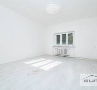 Üres szoba fehér falakkal és fa dekorációjú padlóval egy 4 szobás lakásban.