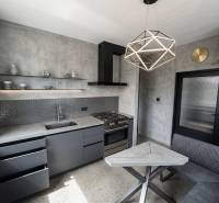 Beton megjelenésű konyha kétszobás lakásban geometrikus lámpával.