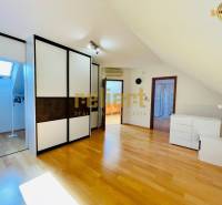 Tetőtéri szoba fa dekoros padlóval és beépített szekrénnyel egy családi házban.