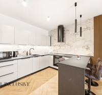 Konyha fehér szekrényekkel, szigettel és fa hatású padlóval egy 4 szobás lakásban.