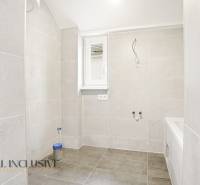 Fürdőszoba családi házban nagy formátumú világos csempékkel.