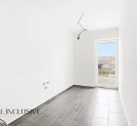 Családi ház belső tere csempével, fehér falakkal és teraszra nyíló ajtókkal.