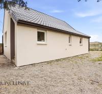 Családi ház Alsóvámoson fehér homlokzattal és ferde tetővel, köves telken.