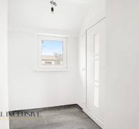 Családi ház előszobája ablakkal és világos falakkal, csempézett padlóval.