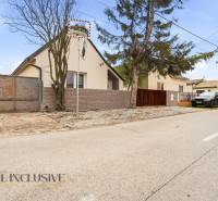 Családi házak Dunaradványon kerítéssel és az út mentén parkoló autókkal.