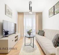 Nappali egy 4 szobás lakásban, fa mintázatú padlóval, világos bútorokkal és kanapéval.