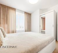 Világos hálószoba egy 4 szobás lakásban fehér szekrénnyel és függönyökkel.