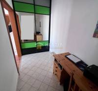 Szoros tér tárolószekrénnyel és faasztallal egy egyszobás lakásban.