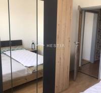 Hálószoba ággyal, szekrénnyel és fa dekoros padlóval egy kétszobás lakásban.