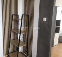 2 szobás lakás belső tere polccal és fa dekorációjú falakkal.