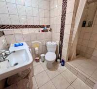 Fürdőszoba egy kétszobás lakásban WC-vel, zuhanyzóval és mosdóval.