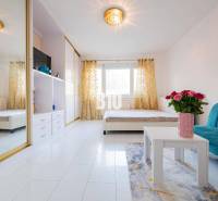 Nappali egy egyszobás lakásban tükörszekrénnyel és fehér padlóval.