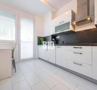 Konyha egy egyszobás lakásban fehér szekrényekkel és sötét munkalappal.