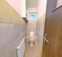 Fürdőszoba egy családi házban, amely tartalmaz egy WC-t és egy lépcsős radiátort.