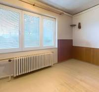 Szoba egy családi házban, világos fallal, ablakkal és fa dekorációjú padlóval.