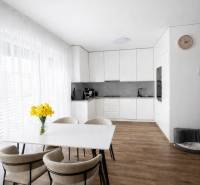 Étkezőasztal székekkel és konyha egy háromszobás lakásban, fa dekorációjú padlóval.