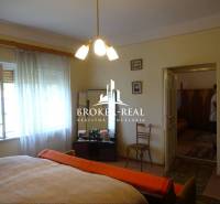 Hálószoba családi házban fa dekor padlóval, ágy, fotel, székek.