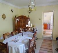 Ebédlő egy családi házban fa bútorokkal, asztallal, székekkel és mennyezeti lámpával.