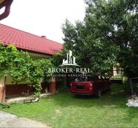 A Goncruszkei családi ház kertje piros tetővel és autóval a gyepen.