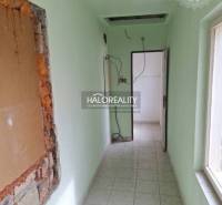 Keskeny belső tér világoszöld falakkal és csempézett padlóval.