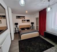 Hálószoba egy családi házban tükörrel, piros függönyökkel és faldekorációkkal.