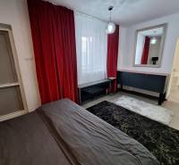 Családi ház belső tere piros függönyökkel, tükörrel és sötét szőnyeggel.