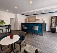 Családi ház belső tere bárpulttal, étkezőasztallal és kényelmes székekkel.