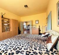 Hálószoba családi házban, leopárdmintás ággyal és fa dekoros szekrénnyel.