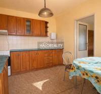 Konyha családi házban beépített szekrényekkel és virágos terítővel ellátott asztallal.