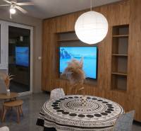 Nappali egy kétszobás lakásban fa dekor padlóval és kerek asztallal.