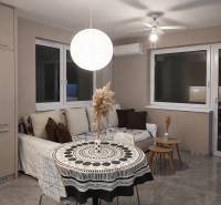 Nappali kanapéval, kerek asztallal és díszes lámpával egy kétszobás lakásban.