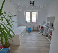 Gyerekszoba családi házban ággyal, asztallal és polccal, fa dekorációval ellátott padlón.