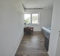 Szoba egy családi házban fa dekorációjú padlóval, székkel és ablakkal.