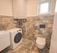 Fürdőszoba családi házban mosdóval, mosógéppel és WC-vel.