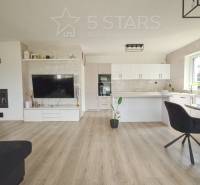 Nappali konyhával a családi házban, világos falak, fa hatású padló.