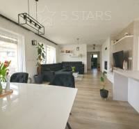 Családi ház belső tere fa dekorációjú padlóval, étkezőasztallal és kanapéval.