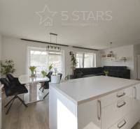 Családi ház belső tere fa dekorációjú padlóval, fehér falakkal és fekete bútorokkal.