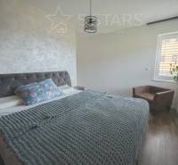 Hálószoba családi házban textil háttámlás ággyal és fa dekorációjú padlóval.