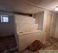 Családi ház belső tere régi kemencével, ablakkal és mennyezeti világítással.