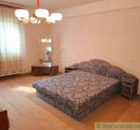 Egy szoba családi házban szőnyeges bútorokkal és tükörrel, fa dekoros padlóval.