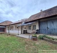 Családi ház Muzslán hagyományos homlokzattal, verandával és buja kerttel.