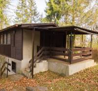 Faház a Holčíkovce-i üdülőterületen, fákkal körülvéve és lehullott levelekkel borítva.