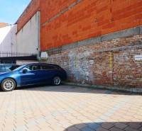 Parkoló a téglaépület mellett a gasztronómiai helyiségekben, Trnava.