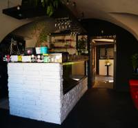 Gasztronómiai tér belső tere fehér bárral, növényekkel és kényelmes ülőhelyekkel.