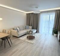 Nappali egy kétszobás lakásban, fa mintázatú padlóval, kanapéval és étkezőasztallal.