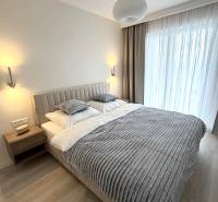 Hálószoba egy kétszobás lakásban fa dekoros padlóval, ággyal és függönyökkel.