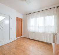 Családi ház belső tere fehér falakkal, ablakokkal és fa dekorációjú padlóval.